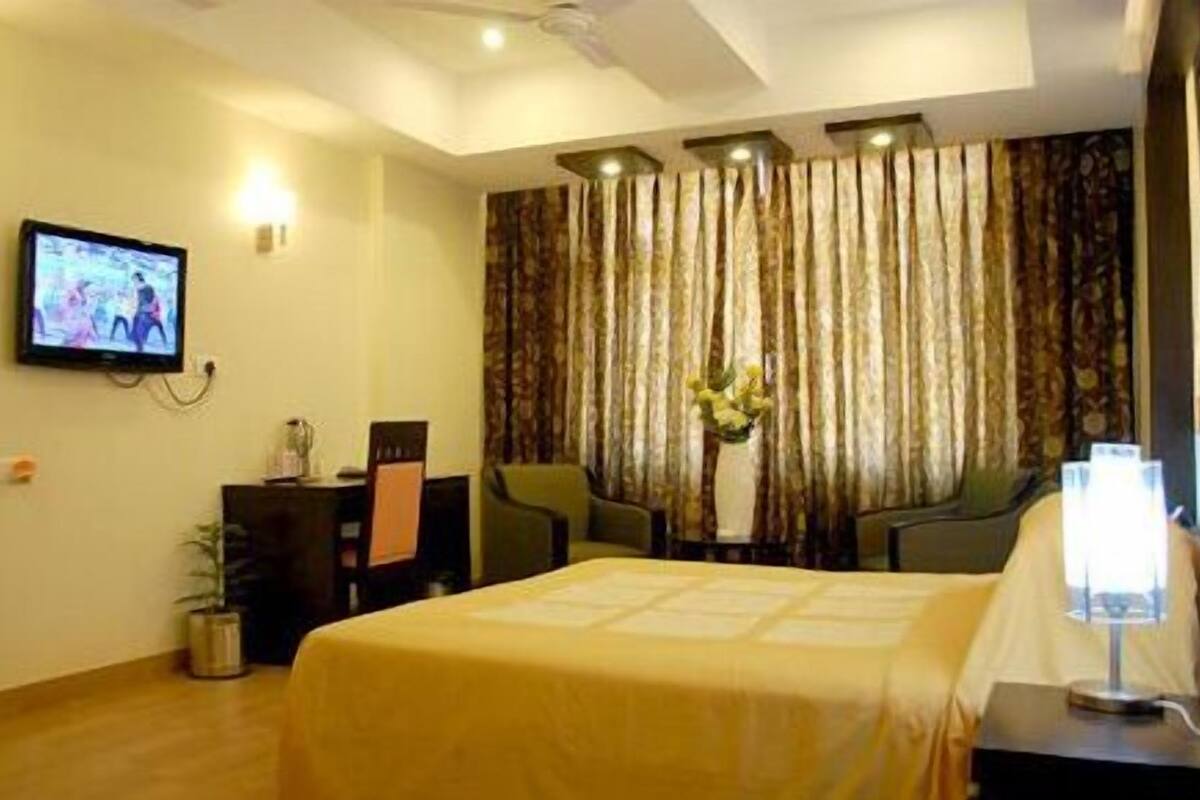 A hotel room with a bed, a television, a desk, and a chair.