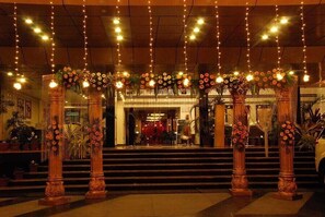 A grand entrance with ornate columns, a staircase, and string lights. - Hotel Softel Plaza (Dehradun)