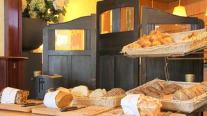 A breakfast buffet with various breads and pastries displayed on wooden boards and baskets.