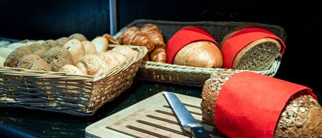 A variety of breads in baskets, a knife, and a cutting board.