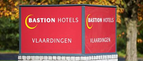 A red sign for Bastion Hotels in Vlaardingen with a crescent logo.