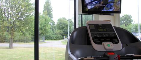 Una cinta de correr con una pantalla digital y una pantalla superior que muestra un paisaje natural.