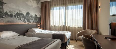 A hotel room with two beds, a desk, a chair, and a large window with curtains.