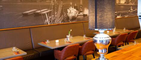 A restaurant with a nautical-themed mural, wooden tables, and leather seating.