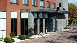 A modern building with a sign reading "Bastion Hotel." It features a brick facade, large windows, and a covered entrance area.
