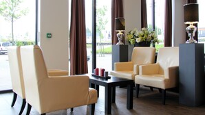 A hotel lobby with leather chairs, a coffee table, and a vase of flowers.