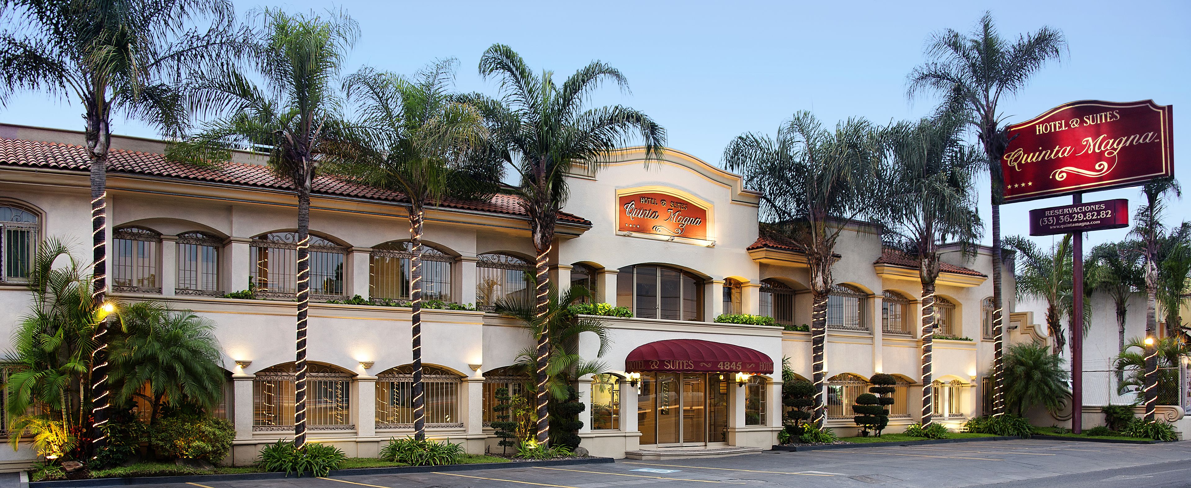 A hotel with a classic Mediterranean architectural style, featuring arched windows and a red awning.