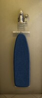 Una tabla de planchar fijada a la pared, con funda azul.