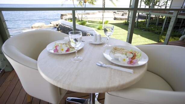 A dining table with plates, glasses, and cutlery on a balcony overlooking the ocean. - Madang Lodge Hotel (Madang)