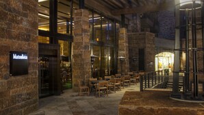A spacious indoor area with stone walls, wooden tables, and chairs arranged for dining.