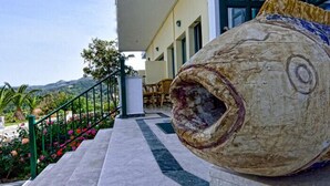 A building with a large fish sculpture on the steps. - Kalidon Panorama (Samos)