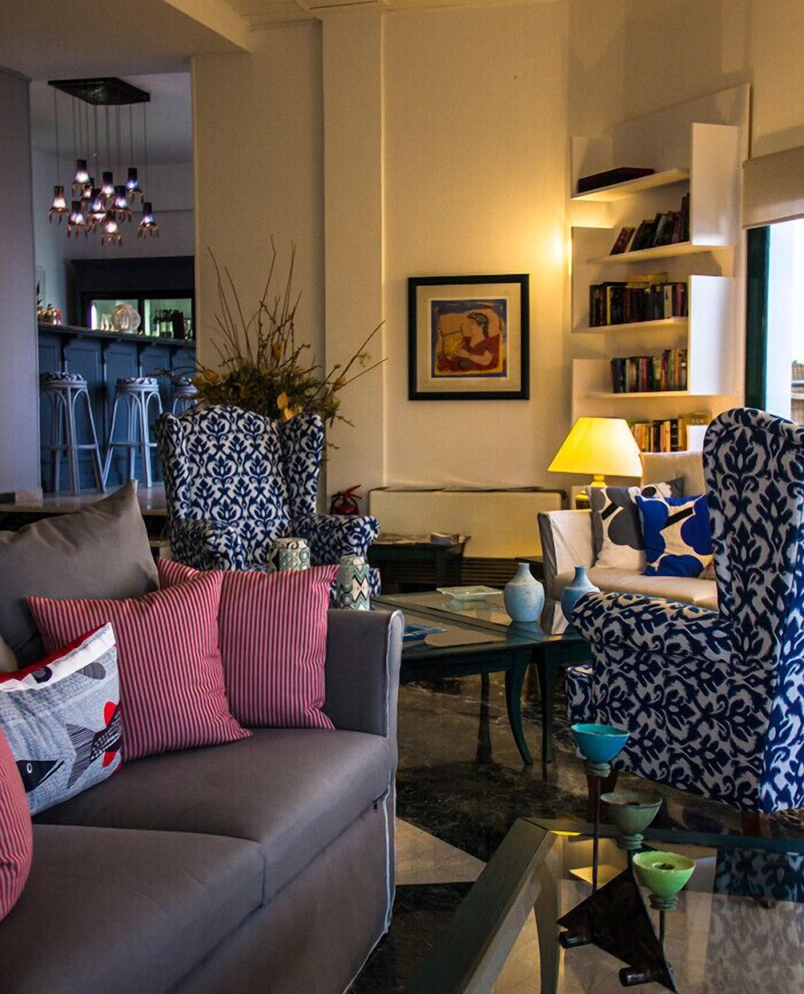 A modern living room with a grey sofa, patterned armchairs, a coffee table, and a bookshelf.