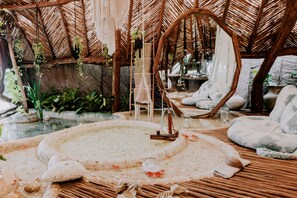 A spa area with a hot tub, seating, and plants.