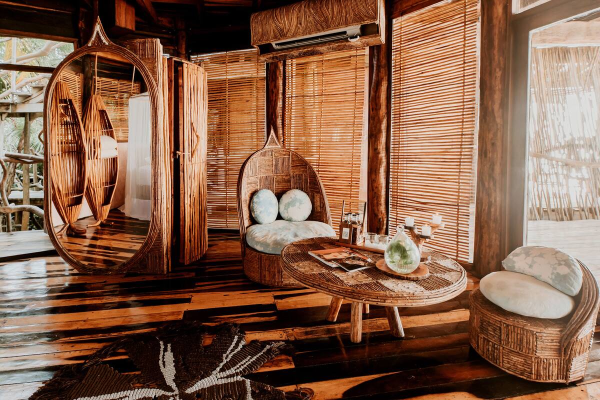 A room with a circular hanging chair, a cushioned chair, and a round table with a decorative item.