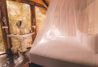 A bed with a canopy, a small table with a decorative base, and a mirror on the wall.