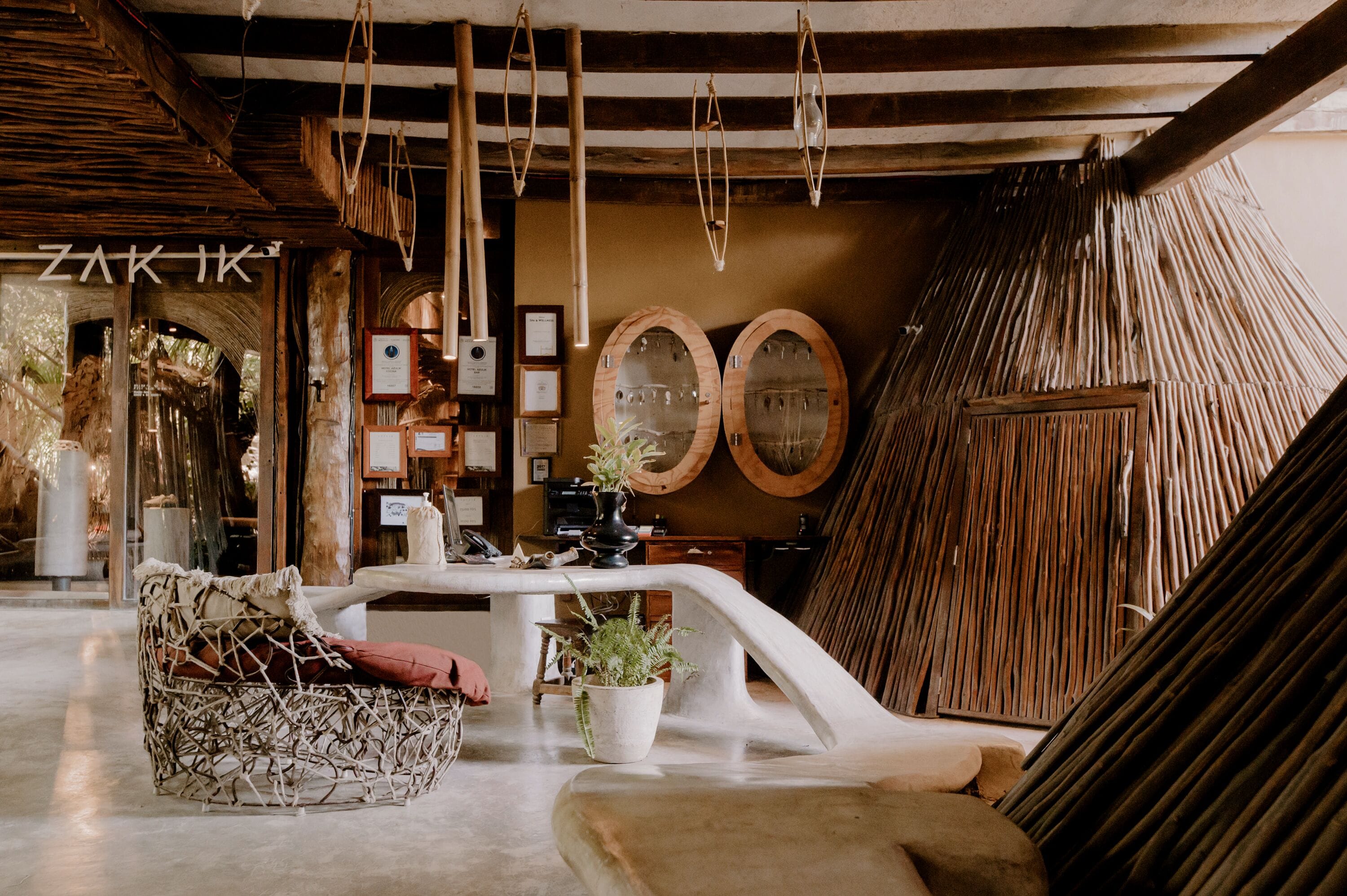 A cozy interior with a woven chair, a table with potted plants, and wooden decor.