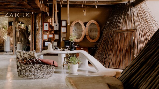 A cozy interior with a woven chair, a table with potted plants, and wooden decor. - Azulik - Adults Only (Tulum)