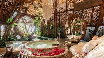 Relax in a serene atmosphere surrounded by lush greenery and a spacious hot tub on a deck.