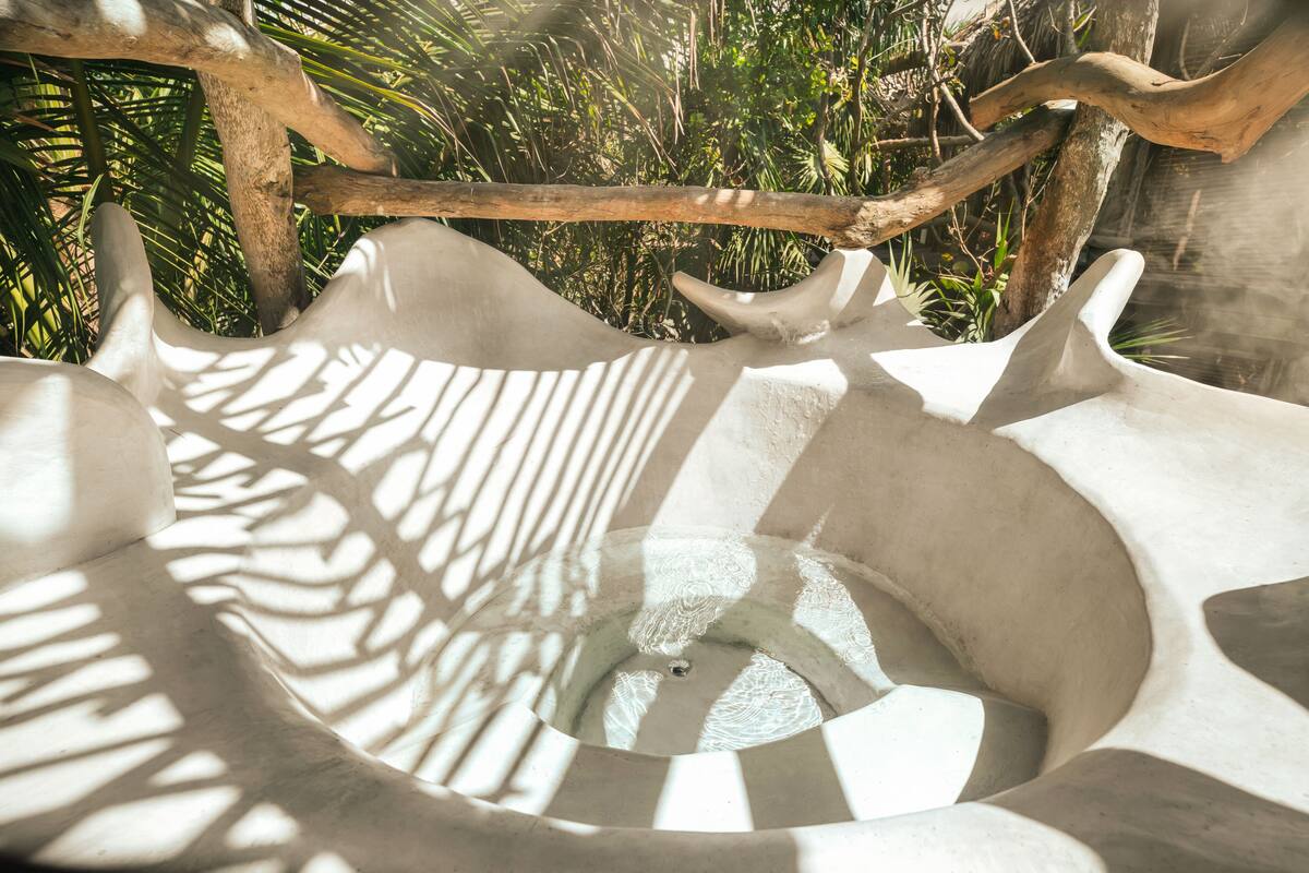 A spiral staircase with a central void, surrounded by natural foliage.