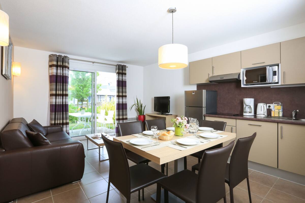 A modern apartment with a dining area, kitchen, and living room.