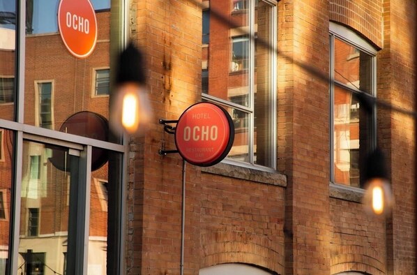 Un letrero de hotel con el nombre 'OCHO' en un edificio de ladrillo.