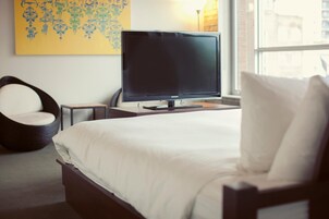 Een hotelkamer met een bed, een televisie, een stoel en een raam.