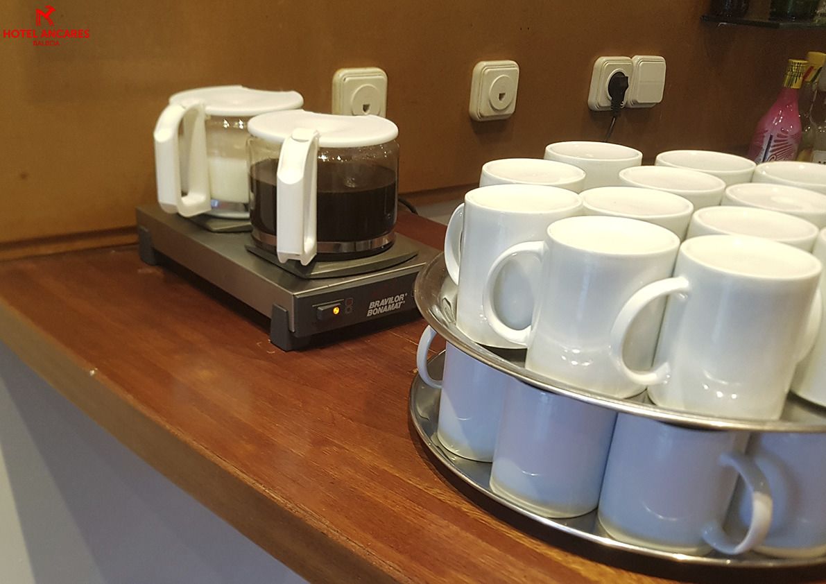 Una estación de café con una cafetera y varios tazas blancas sobre una bandeja.