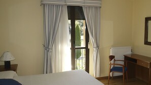 A hotel room with a bed, a desk, a chair, and a window with curtains. - Hotel Ancares (Balboa)