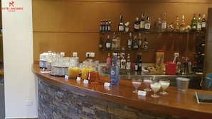 A hotel bar with a stone counter, various beverages, and a selection of liquor bottles. - Hotel Ancares (Balboa)