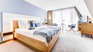 A modern hotel room with a large bed, bedside tables, a desk, and a chair. - Hotel Muschelgrund (Cuxhaven)