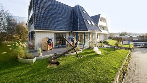 A modern house with a sloped roof, a porch with outdoor seating, and a well-maintained lawn. - Hotel Muschelgrund (Cuxhaven)
