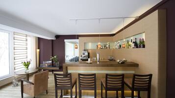 A modern kitchen with a bar area, wooden bar stools, and a dining table with chairs.