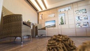A room with wicker chairs, wooden flooring, and a wall decorated with framed pictures. - Hotel Muschelgrund (Cuxhaven)