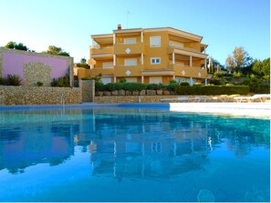 A multi-story hotel with a swimming pool in front.