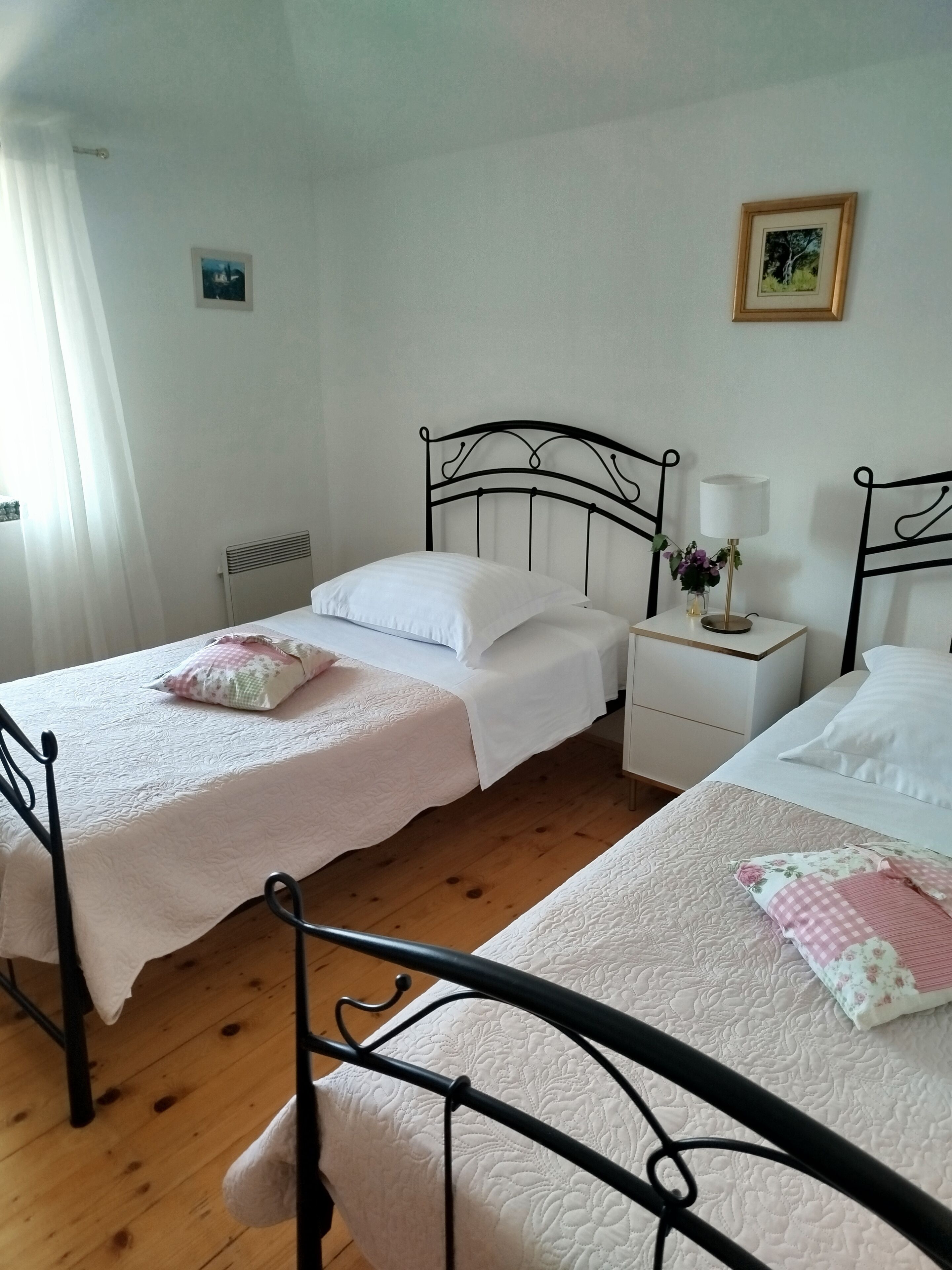Una cama doble con cubrecama blanco y una cama individual con cubrecama floral.