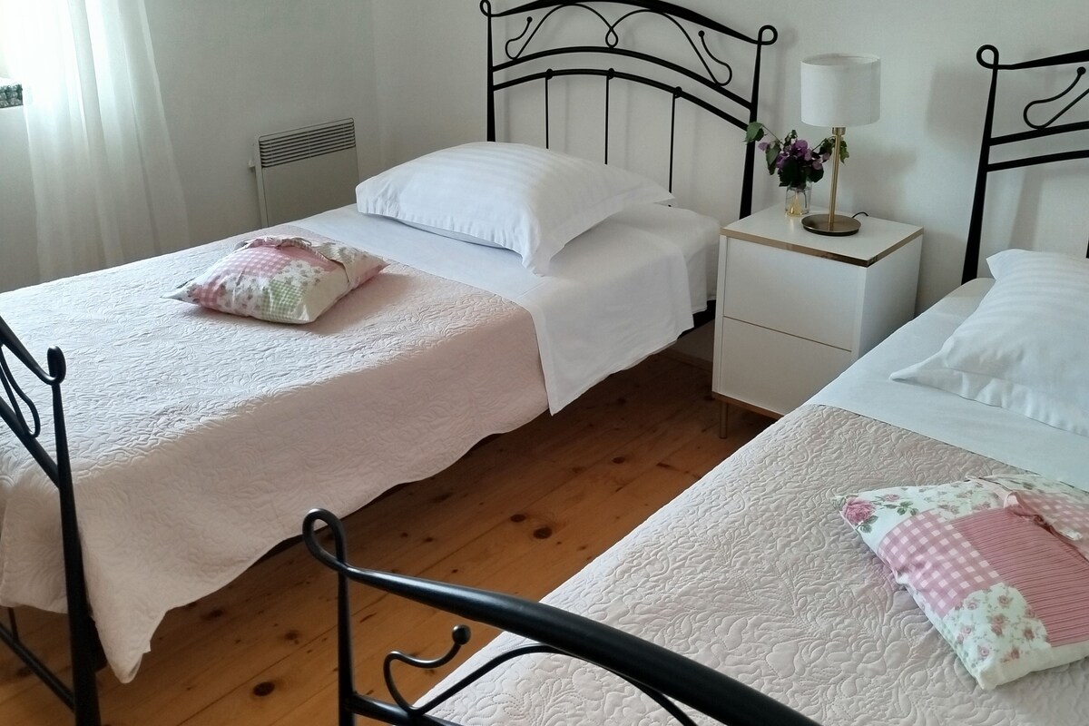 A double bed with a white bedspread and a single bed with a floral bedspread.