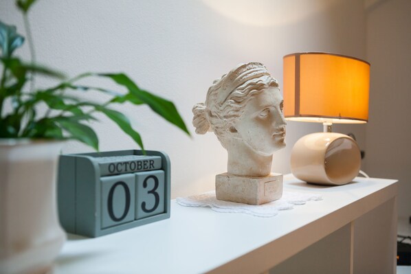 A white shelf with a bust sculpture, a clock displaying October 03, and a lamp. - In The Palace (Split)