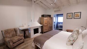 A bedroom with a large bed, a wooden wardrobe, a small table, and a chair.