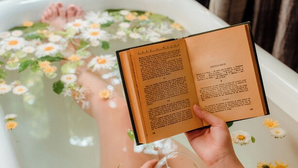 A bathtub filled with water and flowers, with a book held by a person. -  Finca Adalgisa Wine Hotel (Chacras de Coria)