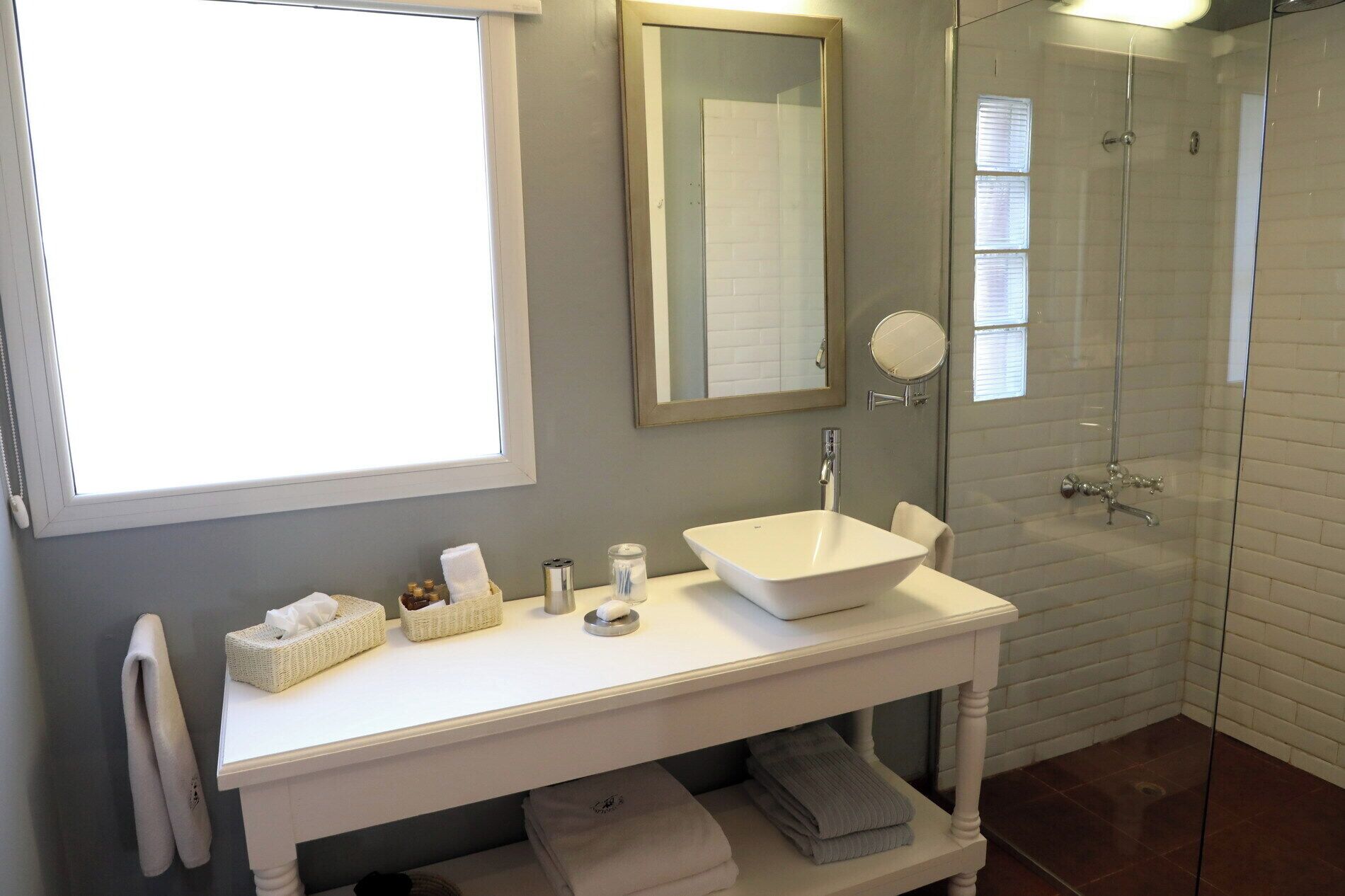 Une salle de bain avec un lavabo blanc, un miroir et une douche à parois de verre.