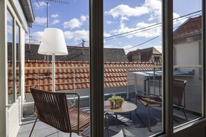 Un balcón con una mesa, dos sillas y una lámpara.