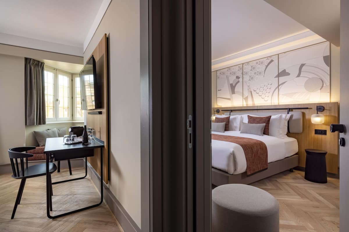 A hotel room with a bed, a desk, and a chair.