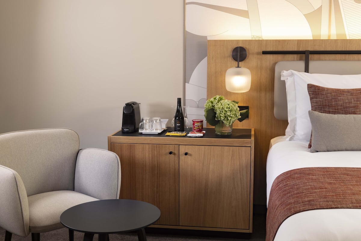 A hotel room with a bed, a small wooden nightstand, a table, and two chairs.