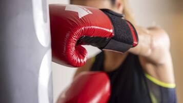 Gros plan sur des gants de boxe rouges posés sur un sac de frappe.