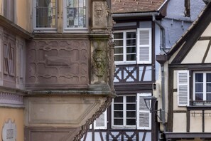A corner of a building with a stone facade and a carved stone ornament.