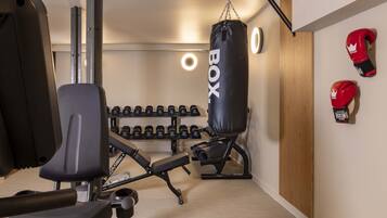 A gym with a punching bag, weight bench, and dumbbells.