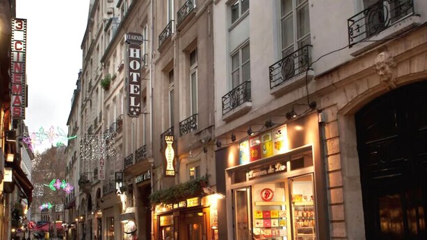 Una calle con un hotel, una cafetería y diversas tiendas.