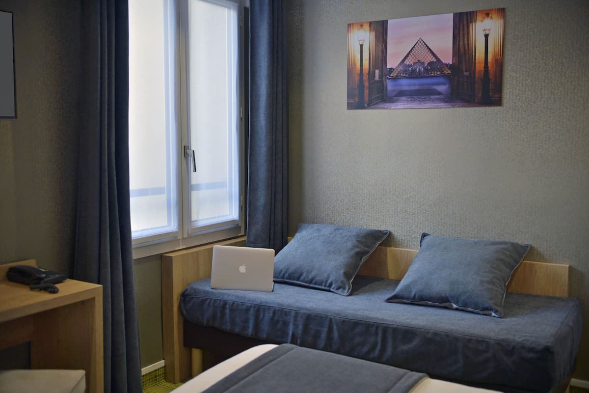 Une chambre d’hôtel avec un lit, un bureau avec un ordinateur portable, un téléphone et un tableau accroché au mur.