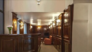 Un vestíbulo de hotel con una recepción, zona de estar y paneles de madera.