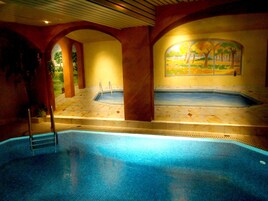 Una piscina techada, sillones reclinables de piscina